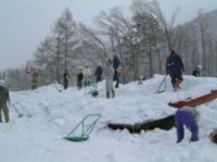 プール更衣室の屋根まで積もった雪を除雪するボランティア